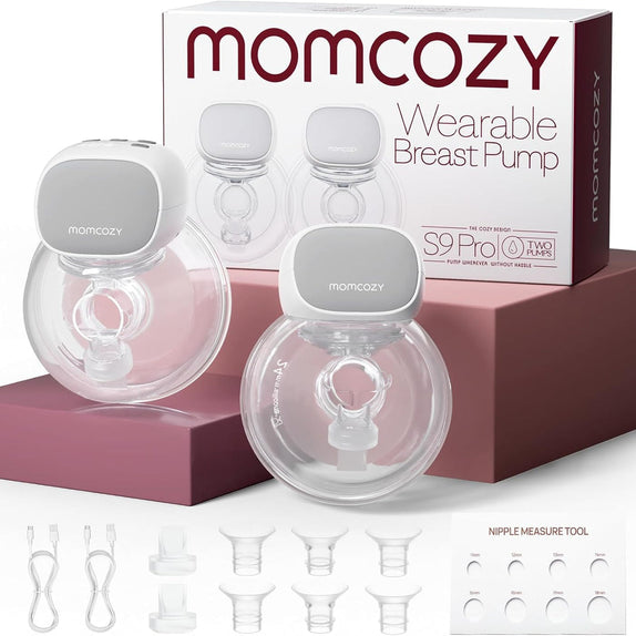 Two Momcozy S9 ProL breast pump devices with clear cups and gray tops, shown in front of their retail box. The image also includes several clear nipple tips and a nipple measurement tool.