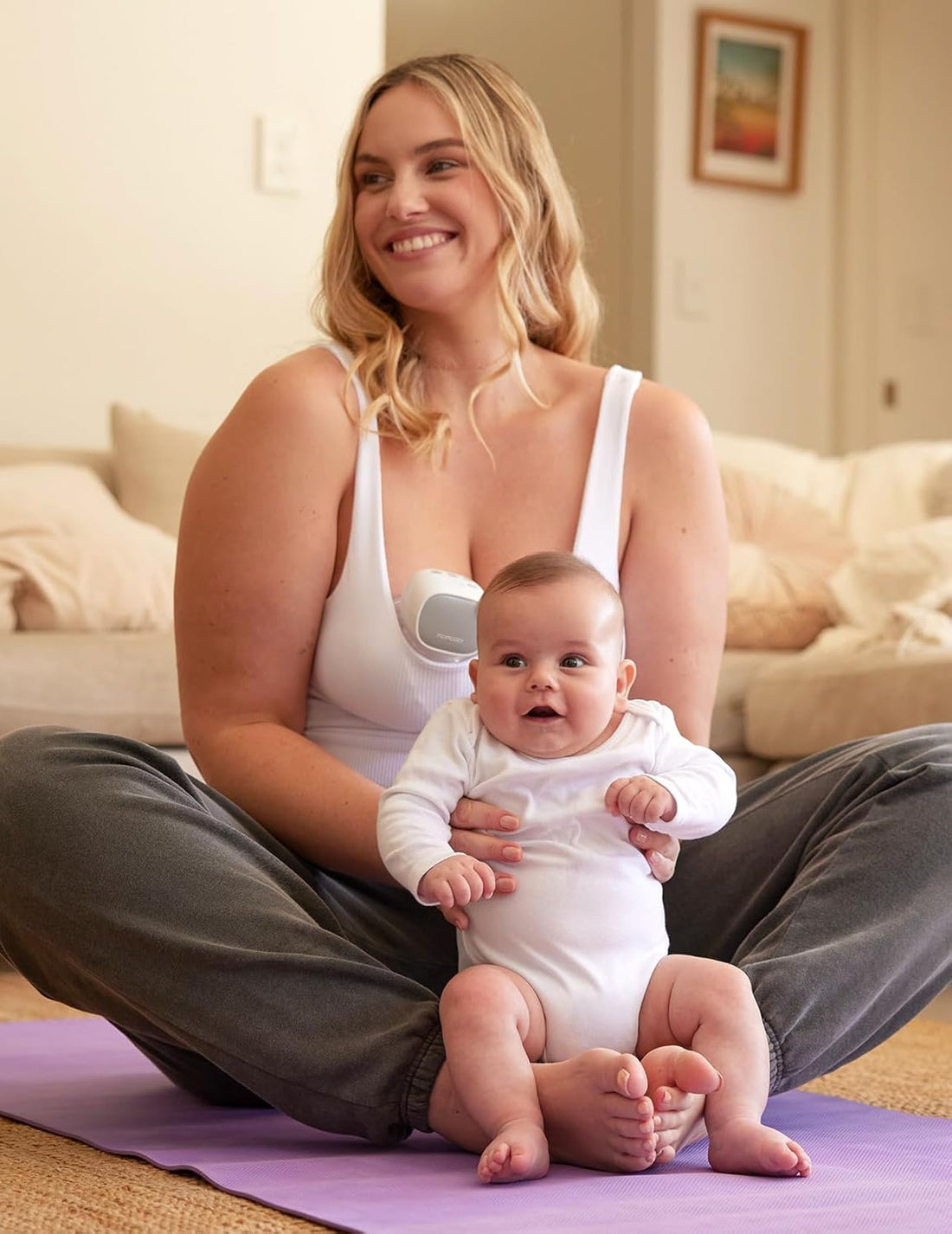 Woman sitting on a yoga mat with a baby on her lap, wearing momcozy S9 breast pump