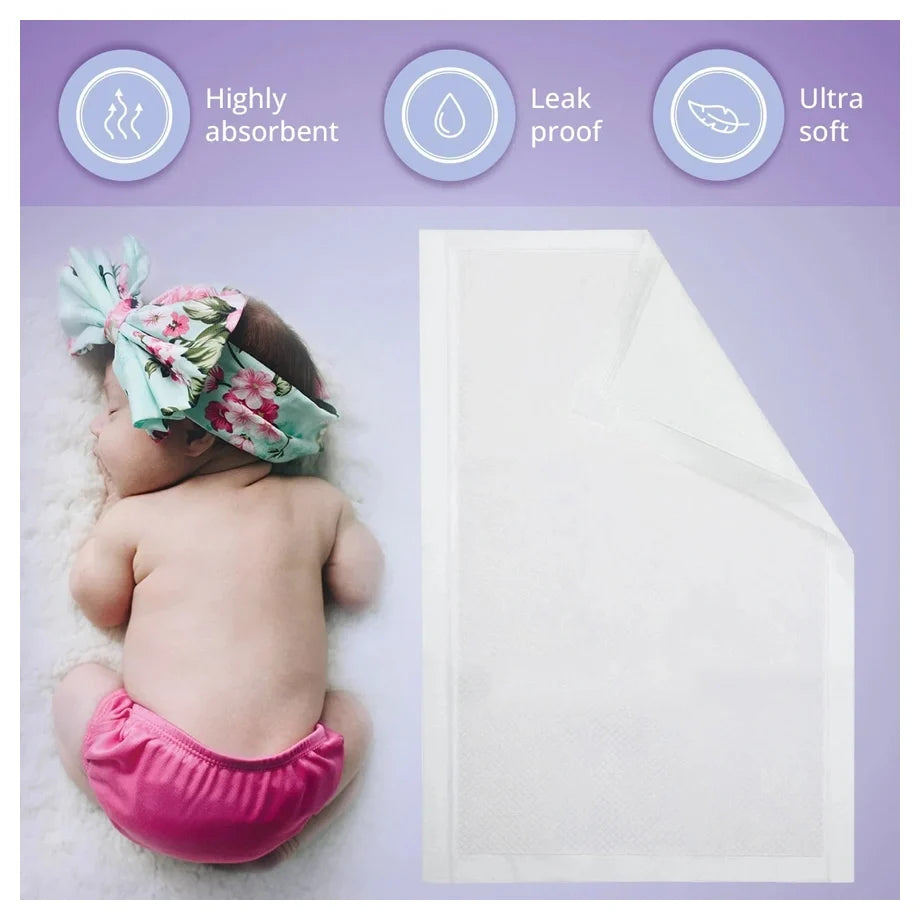 A baby wearing a pink diaper and a floral headband lies on a white blanket next to a white absorbent diaper pad, with three feature icons at the top reading Highly absorbent, Leak proof, and Ultra soft.